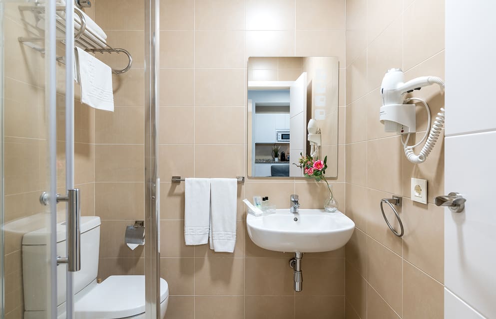 Front view of the washbasin in one of the Hoteles del Sur apartments, with a wall-mounted hairdryer.