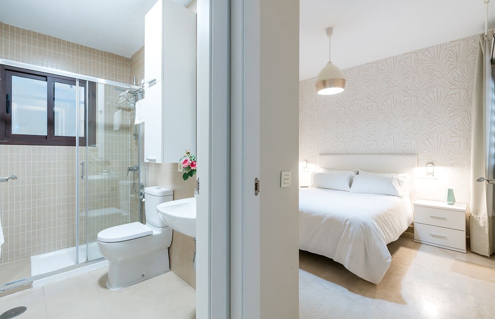 Interior of an apartment showing the living room on one side and the bathroom on the other, separated by a short section of wall.