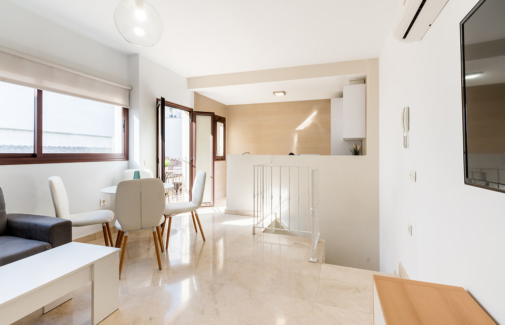 General view of the living-dining room in one of the apartments, with access to the terrace and an open-plan kitchen