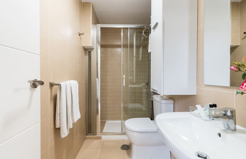 Bathroom with shower, featuring sand-coloured tiling