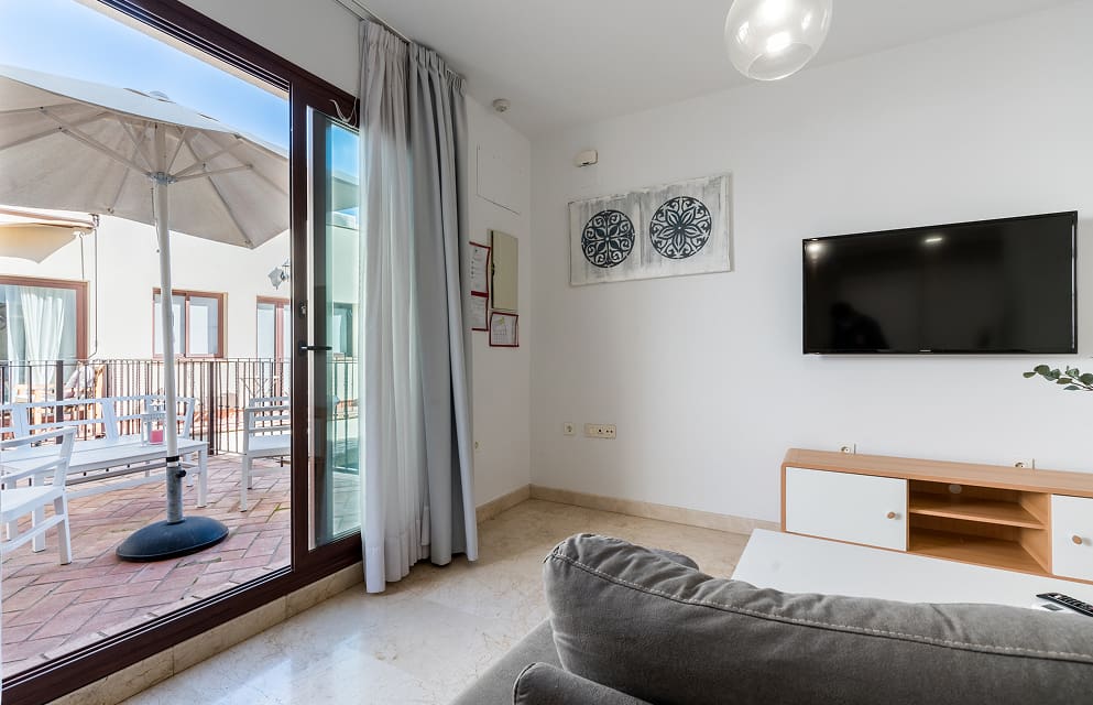 Living-dining room opening onto a spacious terrace, with a large parasol and outdoor furniture