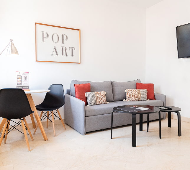 Dúplex com varanda Sala com sofá de dois lugares, uma mesa com duas cadeiras e um quadro de pop art