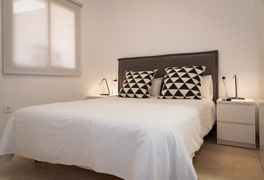 Duplex com Varanda | Cama de casal Cama de casal com lençóis brancos e almofada com padrão preto e branco
