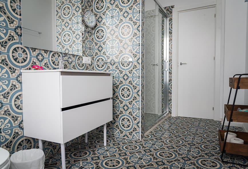 Apartamento Suite | Casa de banho Casa de banho decorada com azulejos tipo hidráulico, com duche e espelho de aumento
